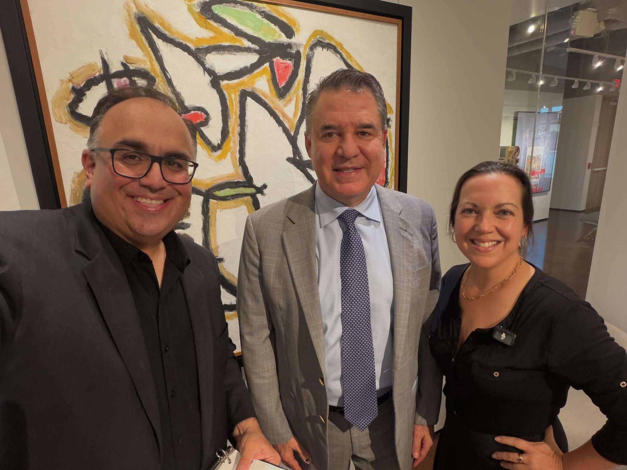 Mike Acosta, Mauricio Vallejo and Lisbet Newton posing in front of an abstract painting at the Arrival Awards kickoff.