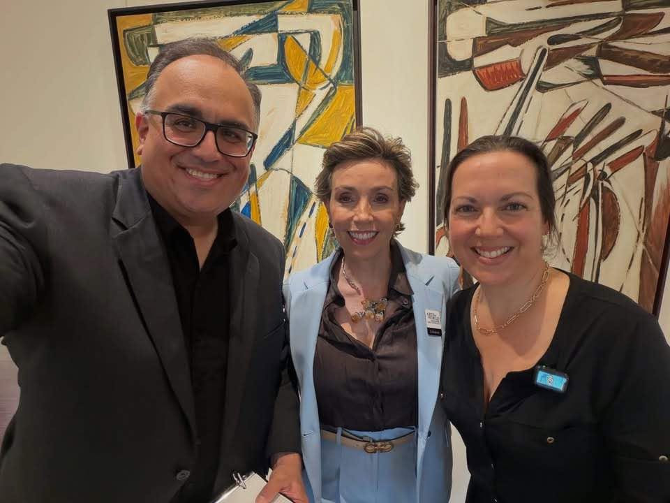 Mike Acosta, Liliana Molina and Lisbet Newton smiling together in front of paintings at the Arrival Awards kickoff.