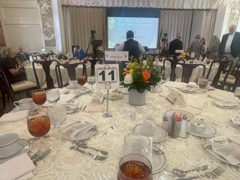 Guests gather around tables with floral centerpieces at the Fall Harvest Luncheon at the Junior League of Houston.